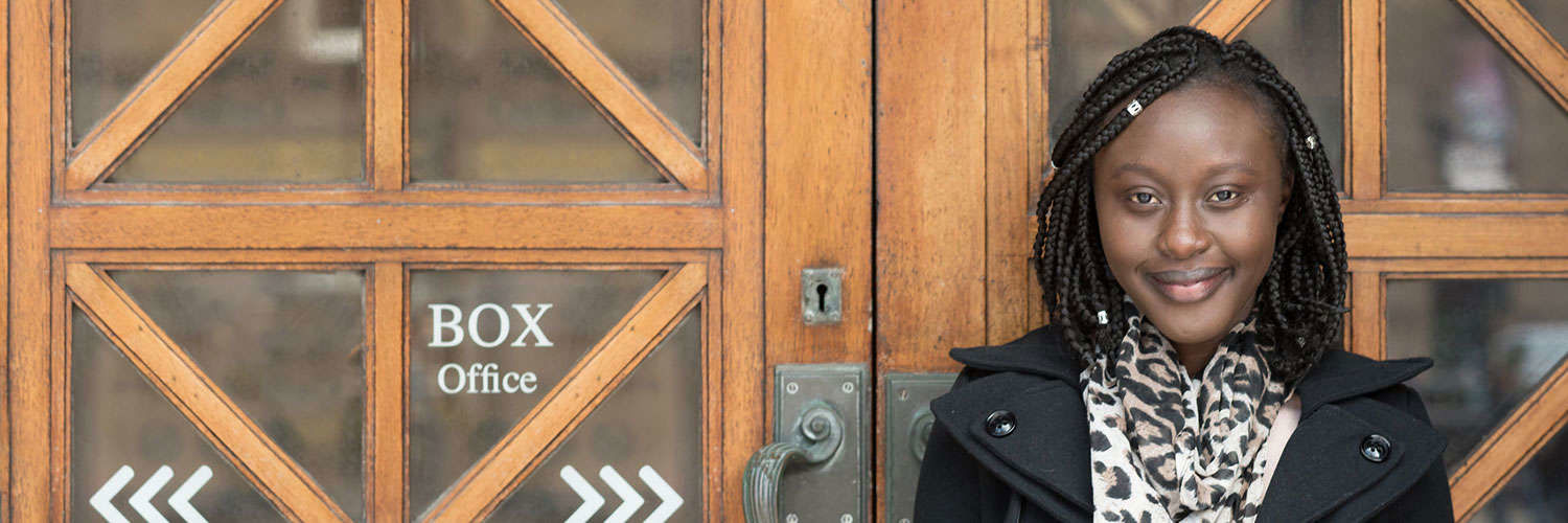 A young woman smiling for the camera beside a door