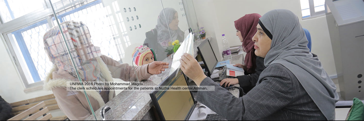 A receptionist handing something through a glass panel to someone on the other side