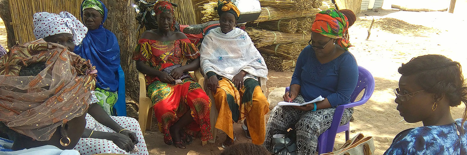 A group of African women sitting in a circle wearing their brightly coloured native clothing