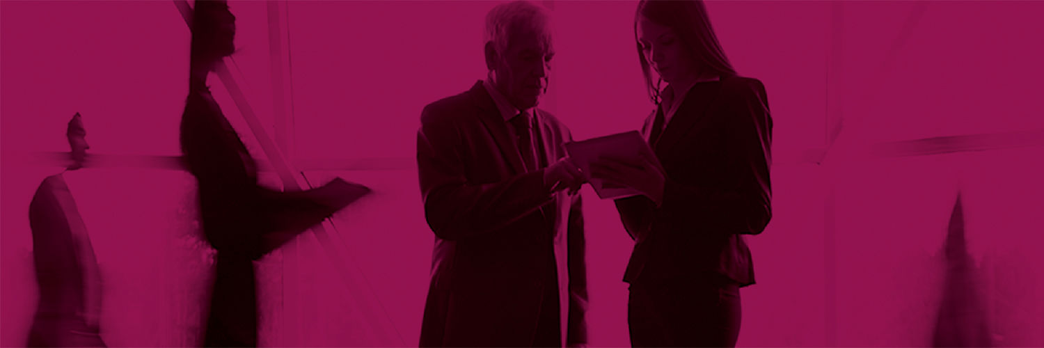 A black and pink photo of two professionals looking at paperwork as blurry people walk around them