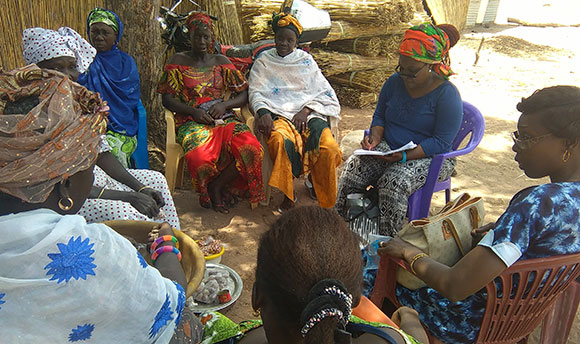 A group of African women sitting in a circle wearing their brightly coloured native clothing