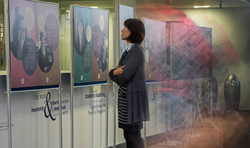 A woman looking up at a picture in a showcase on Women in Research