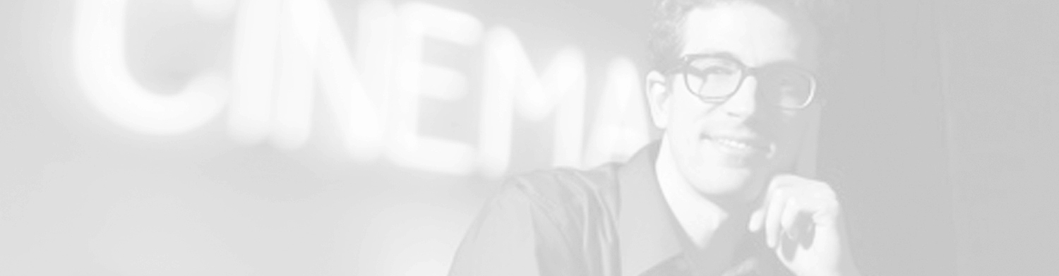 Greyscale image of a smiling young man in glasses