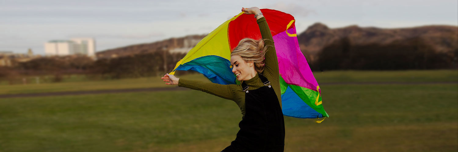 A smiling woman playing with a kite