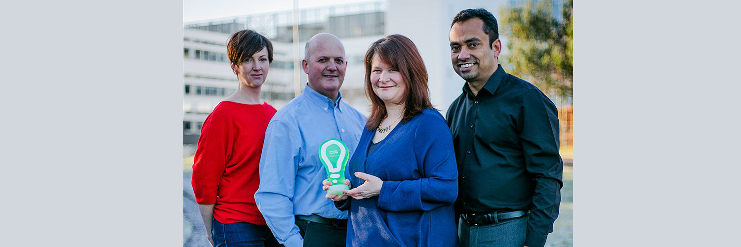 A small group of people standing outside QMU holding a small award