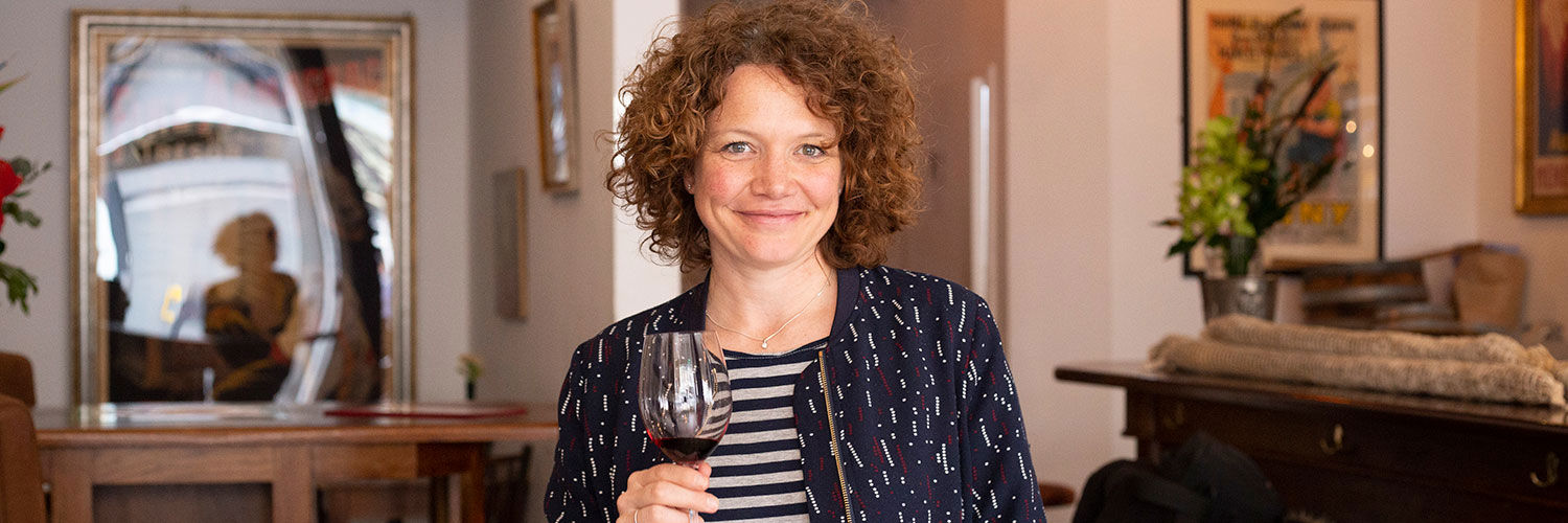 Nikki Welch founder of Quenchable holding a glass of wine in lounge