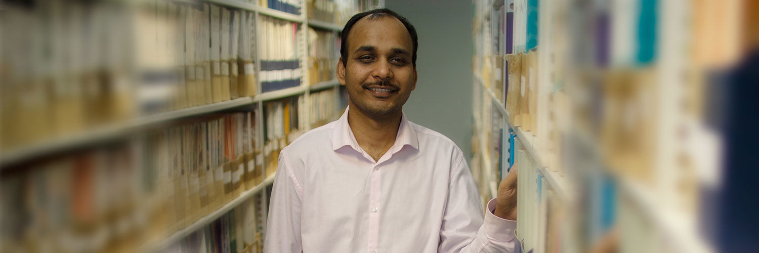 QMU student between bookshelves of campus library