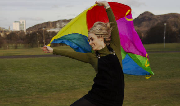 A smiling woman playing with a kite