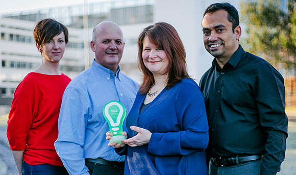 A small group of people standing outside QMU holding a small award