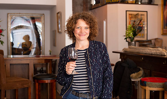 A smiling woman holding a glass of red wine