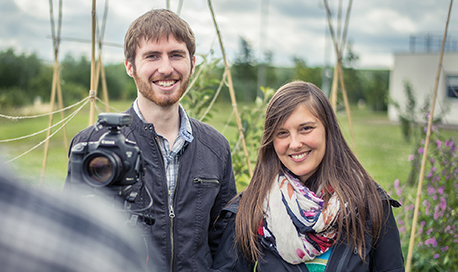 A young man and woman outside QMU campus with a professional camera