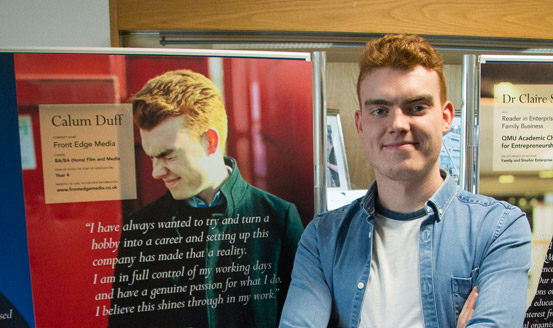 Calum Duff standing by a poster he is on