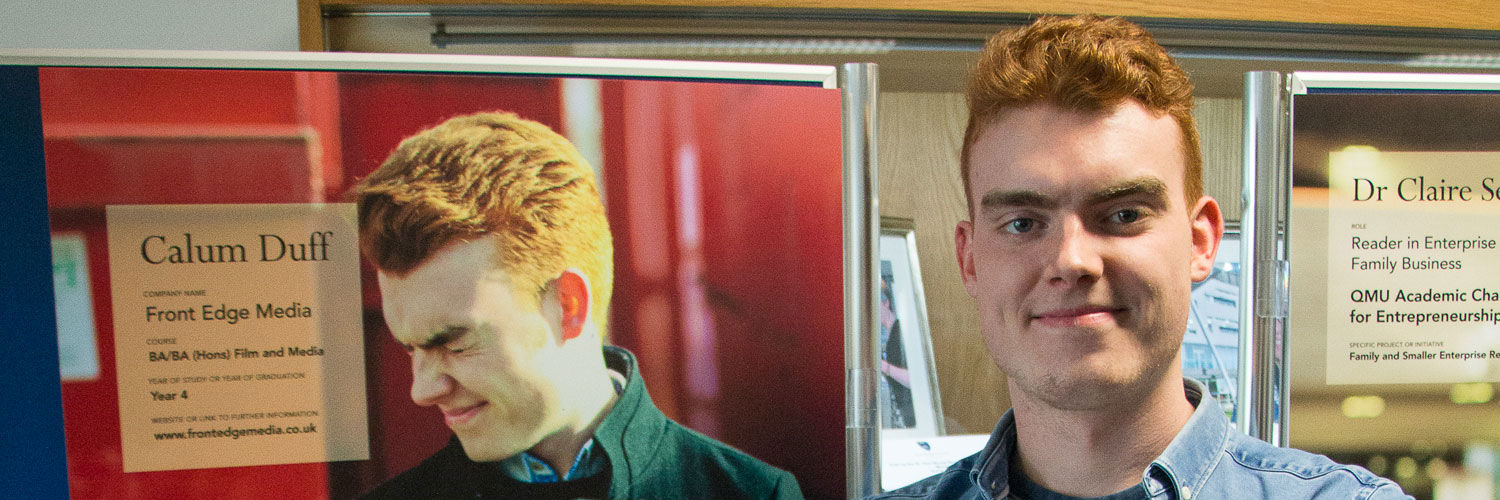 Calum Duff standing by a poster he is on
