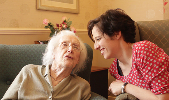 A young woman chatting with an elderly woman in a care home