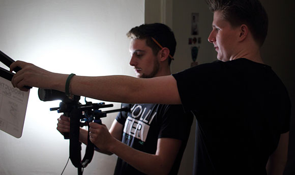 Two QMU students, one setting up a camera and the other holding the clapper board in front of the lens