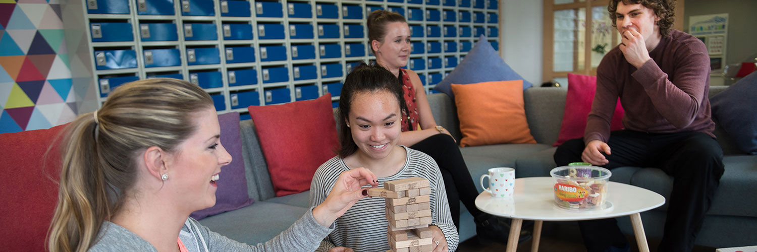 QMU students playing jenga whilst others have tea and biscuits beside them