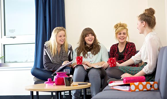A group of young QMU students on a sofa chatting