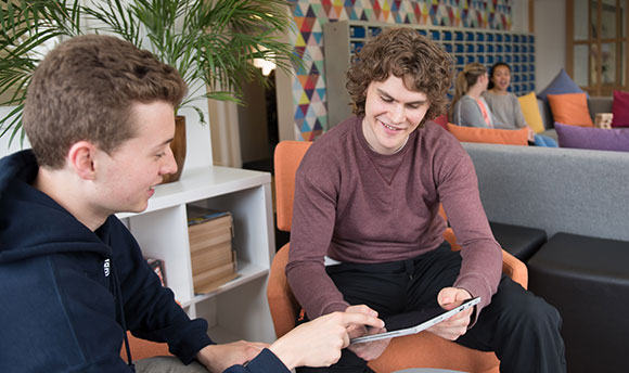 Some QMU students looking at an iPad together in the common space of their accommodation