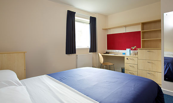 The premium room layout, with a double bed, en-suite, desk, wardrobe and drawers