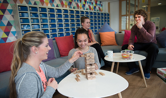 QMU students playing jenga whilst others have tea and biscuits beside them
