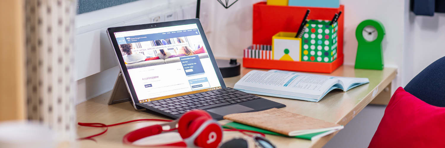 A laptop and headphones on a student desk in Queen Margaret University accommodation