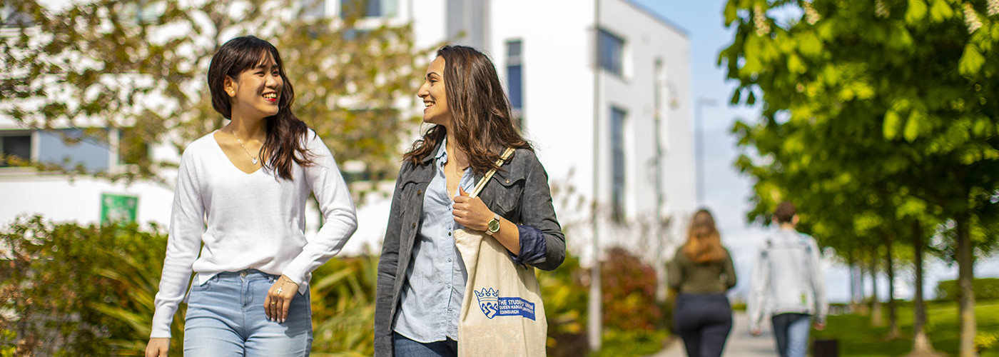 Two Queen Margaret University students walking down an outdoor path on campus