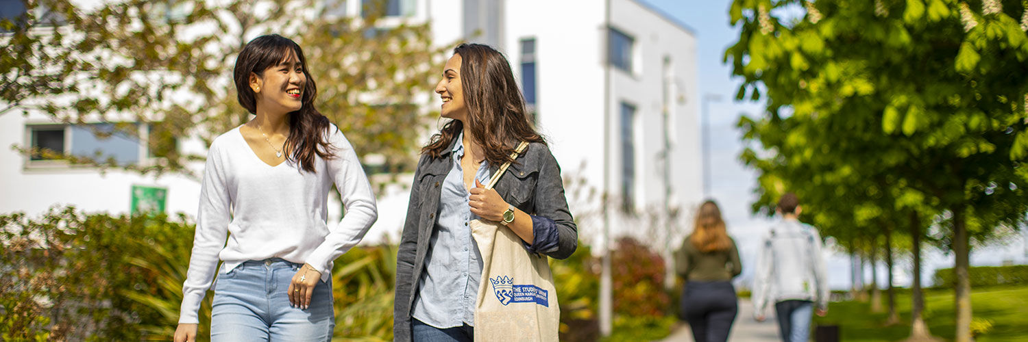 Two Queen Margaret University students walking down an outdoor path on campus