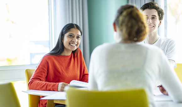 A small group of Queen Margaret University students sitting at a table, talking