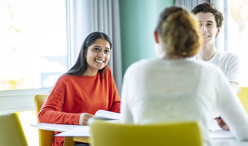 A small group of Queen Margaret University students sitting at a table, talking