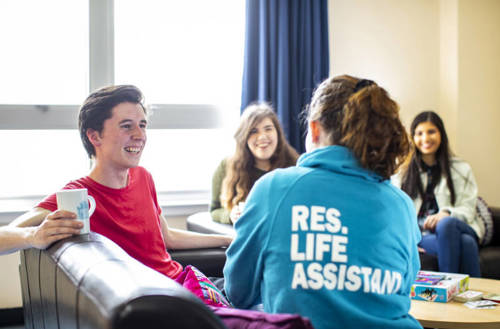 A student having a cup of tea with a friendly Res Life representative