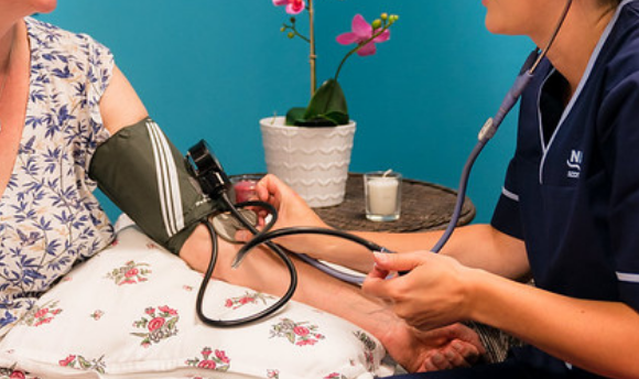Medical staff using blood pressure gauge on patient