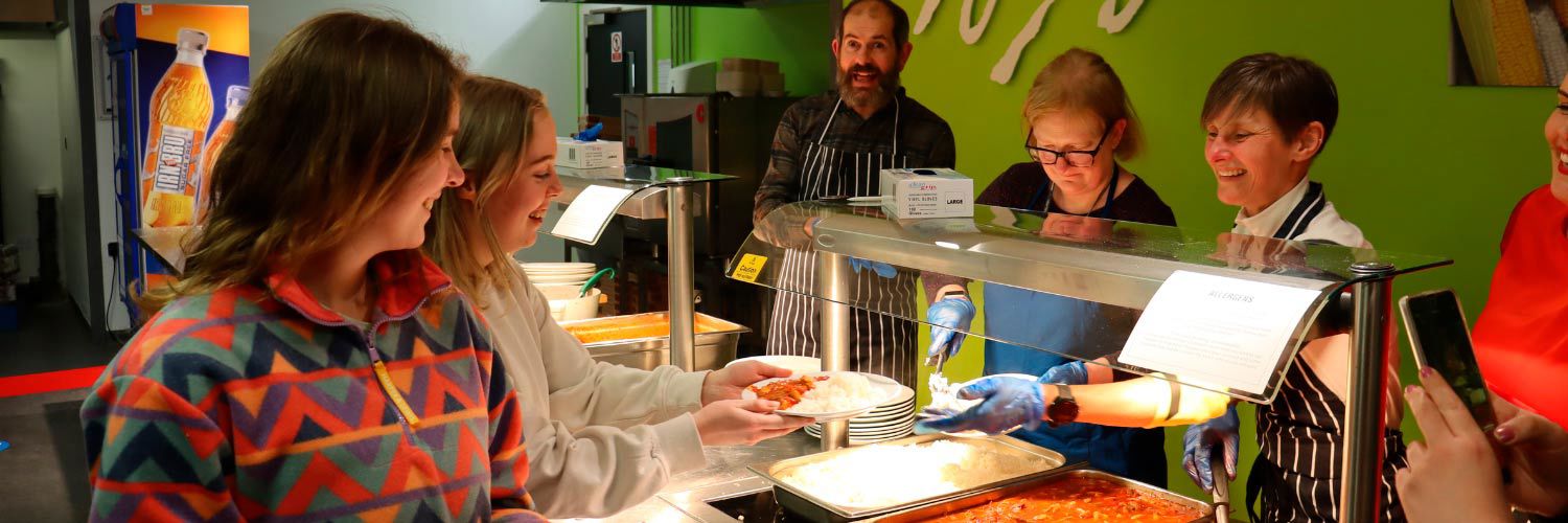 Two students being given food by volunteers from Queen Margaret University