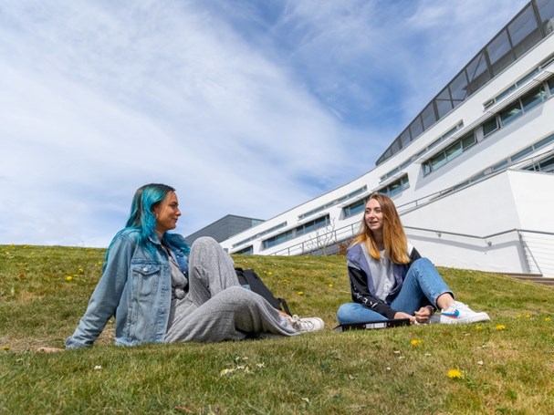 Image of students sitting outside QMU in the sunshine