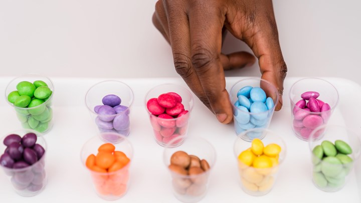 Samples of different coloured sweets divided in plastic cups