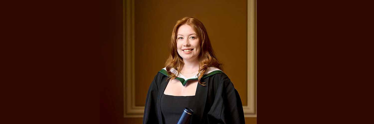 Portrait shot of student Tasmin McCallum with long red hair in black graduation robe