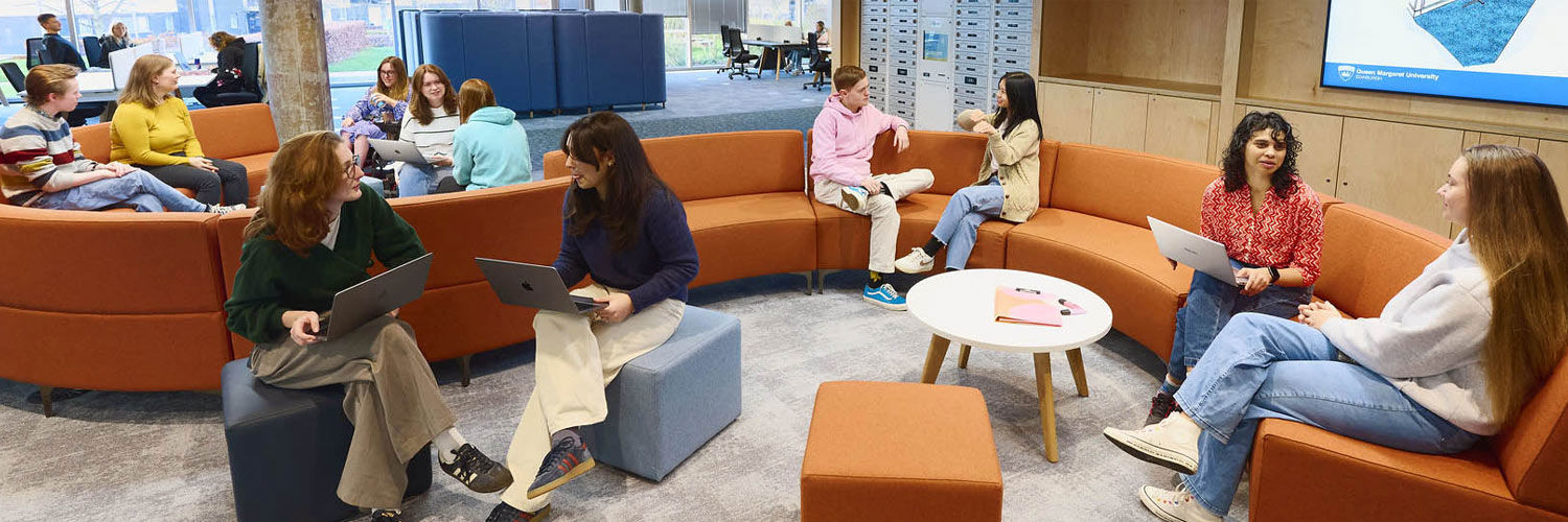 Several students sitting on the curved sofas within the library.