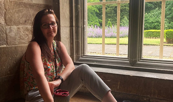 Girl sitting in a relaxed position with a backdrop to the gardens at Newbattle Abbey College