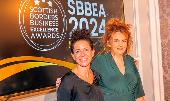 Two people posing in front of a banner for the Scottish Borders Business Excellence Awards