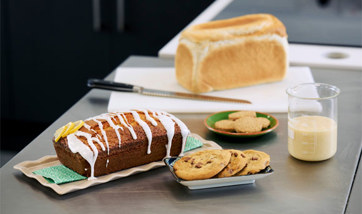 A loaf of bread, a plate of cookies, some biscuits, and a loaf cake created using an alternative to palm oil.