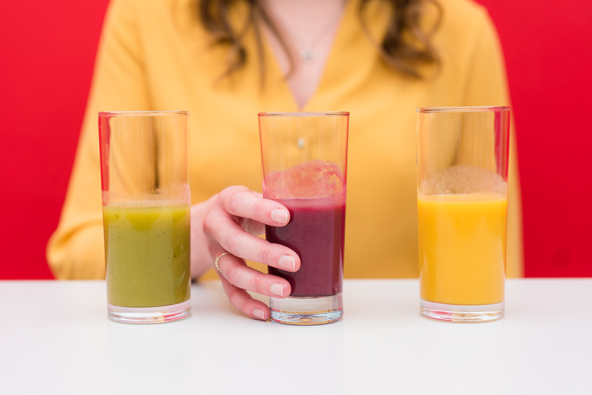 Person with three types of juice in glasses to be tasted