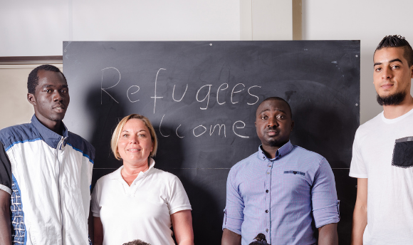 People standing in front of refugees welcome sign