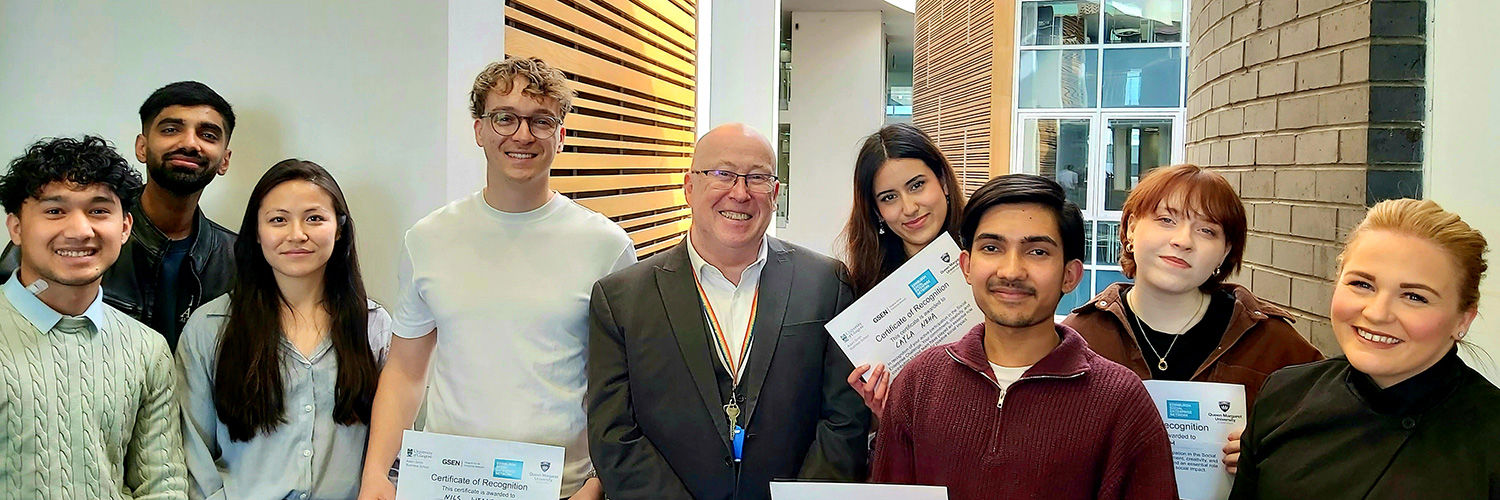 a group of smiling students standing with the Queen Margaret University Principal