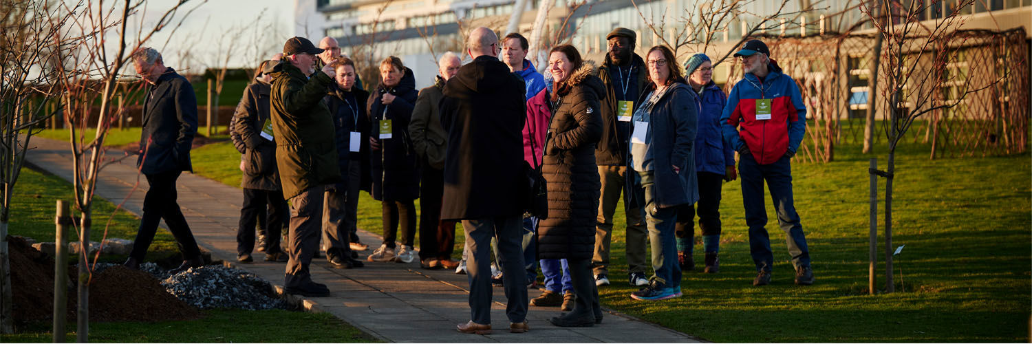 A group of people taking a walk through the QMU campus outdoors.