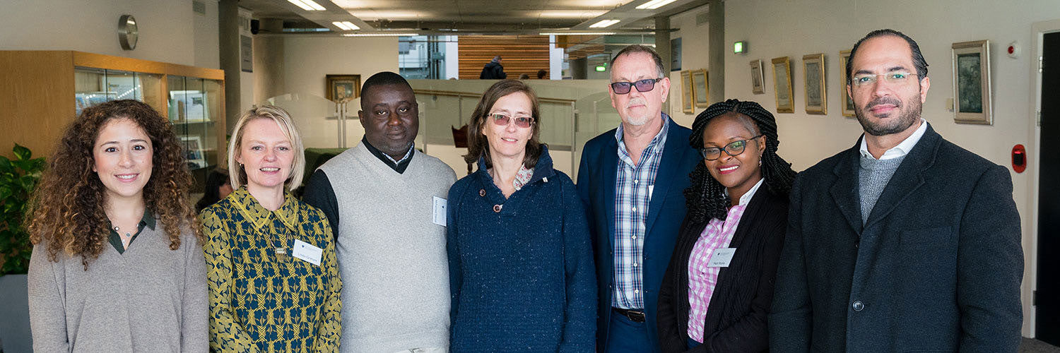 A group of well dressed people stand in a line for photo, smiling