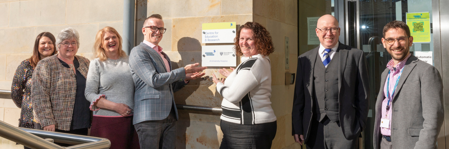 Staff team from St Columba Hospice and Queen Margaret University gather in front of the new University Hospice signage at the entrance to the hospice building