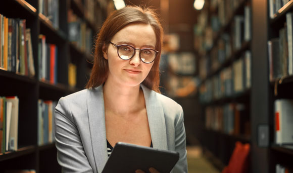 A female student sat on the library floor, surrounded by bookcases