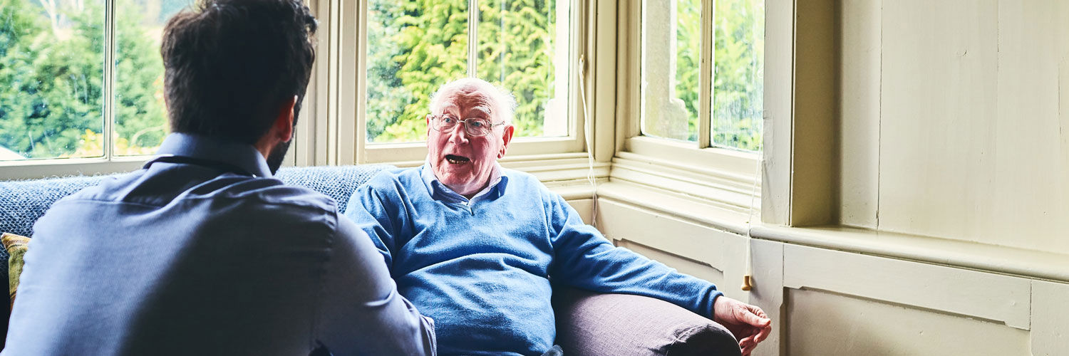 Elderly man in care home talking to staff