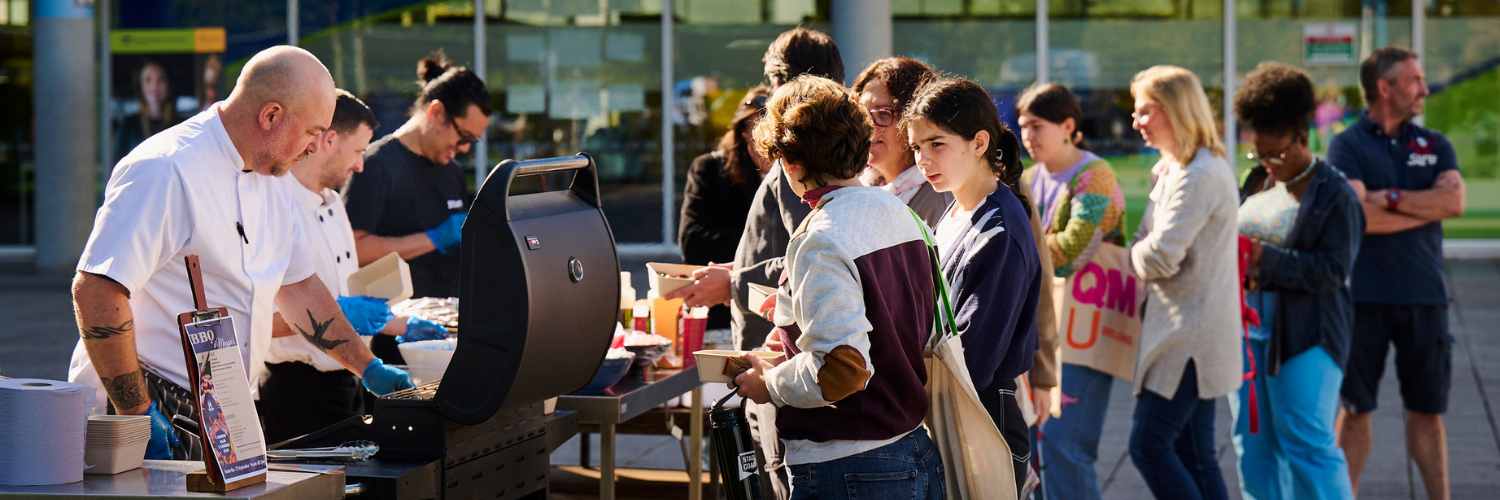 Visitors to campus lining up to get food from the chefs at the outdoor barbeque