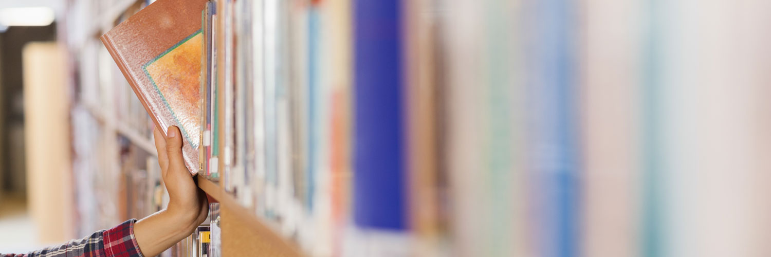 QMU student taking book off a shelf 