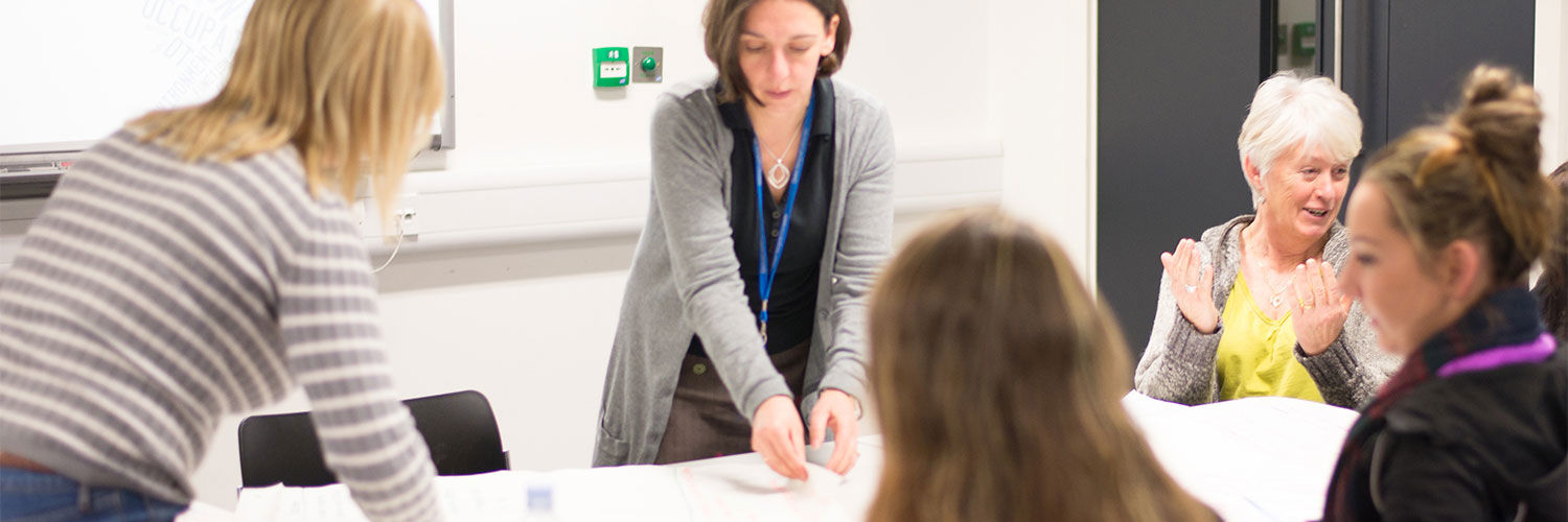 A group of Queen Margaret University Students and lecturer chatting around a table